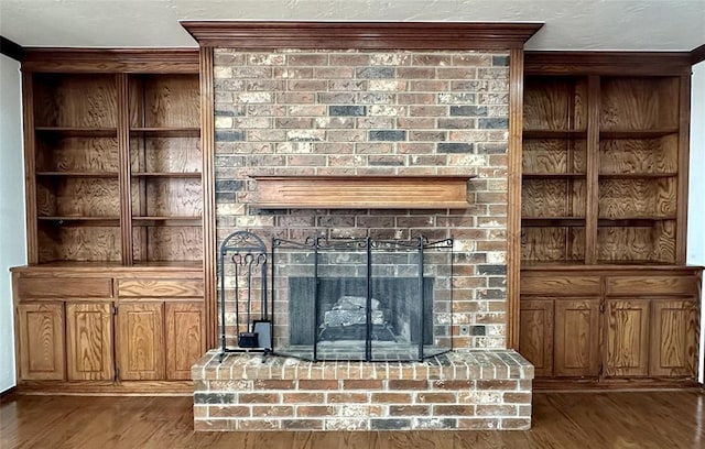 unfurnished living room featuring built in shelves, dark hardwood / wood-style flooring, and a brick fireplace