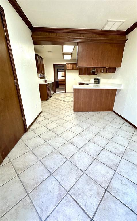 kitchen with light tile patterned floors, ornamental molding, and kitchen peninsula