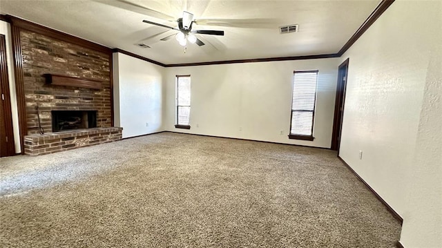 unfurnished living room featuring carpet flooring, ornamental molding, ceiling fan, a brick fireplace, and a healthy amount of sunlight