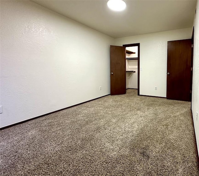 unfurnished bedroom with a spacious closet, carpet floors, and a closet