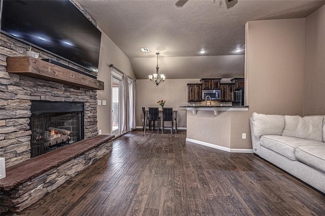 unfurnished living room featuring lofted ceiling, dark wood-type flooring, a textured ceiling, and a fireplace