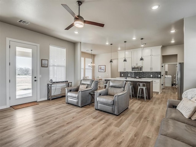 living room featuring sink, ceiling fan with notable chandelier, and light wood-type flooring