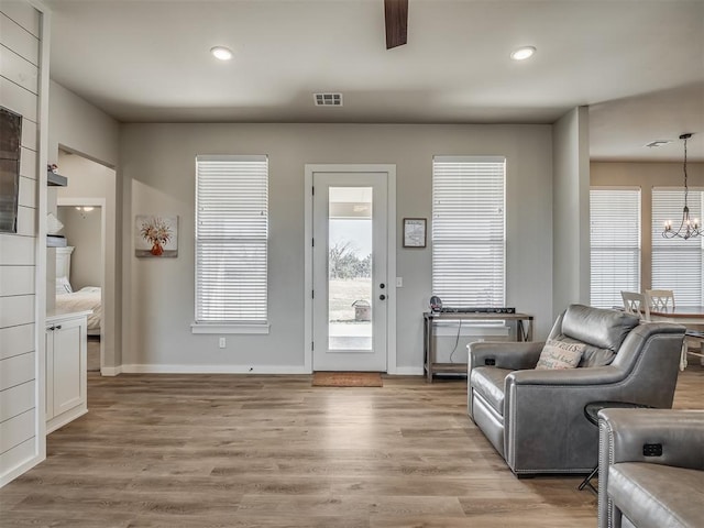 living area with visible vents, baseboards, recessed lighting, light wood-style floors, and a notable chandelier