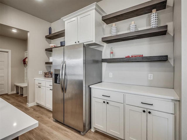 kitchen with open shelves, white cabinets, stainless steel refrigerator with ice dispenser, and light wood finished floors