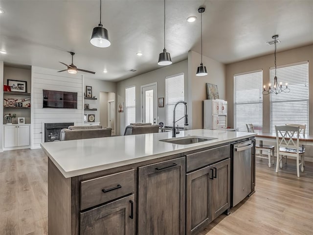 kitchen featuring a sink, ceiling fan with notable chandelier, light wood-type flooring, and stainless steel dishwasher