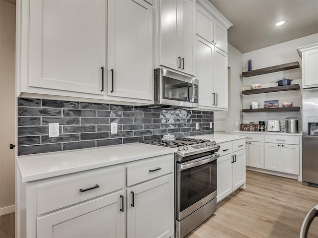 kitchen with open shelves, tasteful backsplash, appliances with stainless steel finishes, light wood finished floors, and light countertops