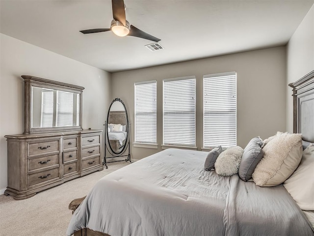 bedroom with visible vents, light colored carpet, and ceiling fan