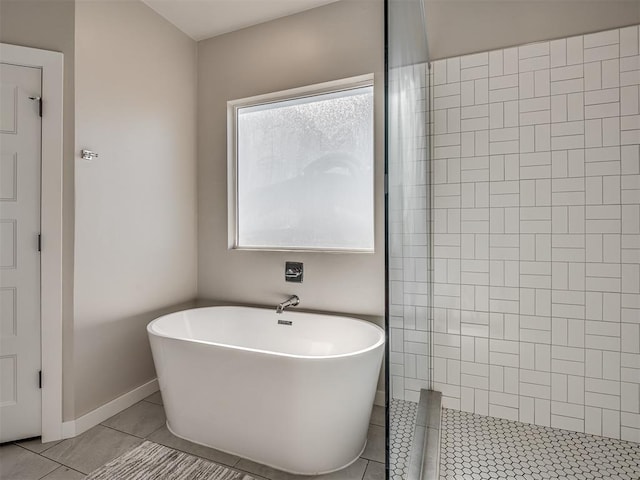 bathroom with tile patterned floors, a freestanding tub, baseboards, and tiled shower