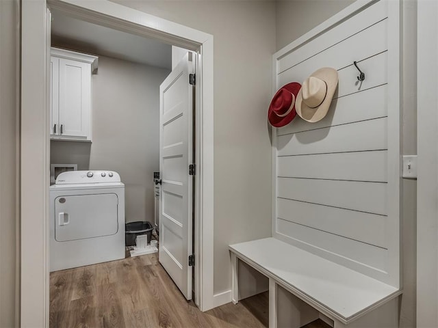 laundry area featuring washer / dryer, light hardwood / wood-style flooring, and cabinets