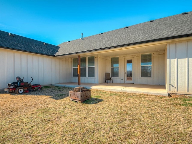 rear view of house featuring a patio, a fire pit, board and batten siding, and a lawn