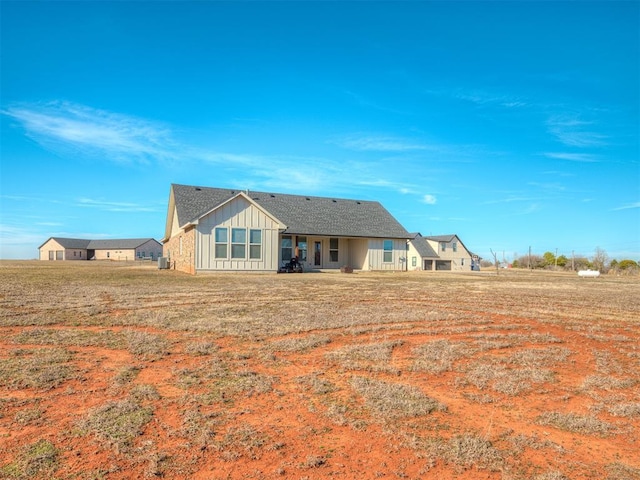 back of property with a lawn and board and batten siding