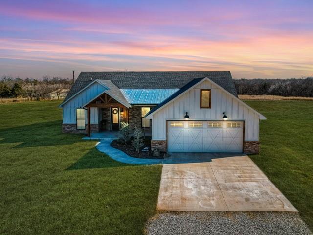 view of front facade with concrete driveway, a front lawn, a garage, stone siding, and board and batten siding