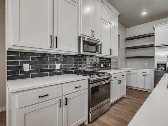 19001 Bobcat Ridge Ct, Cashion, OK 73016 - kitchen with stainless steel appliances, open shelves, light countertops, white cabinetry, and wood finished floors
