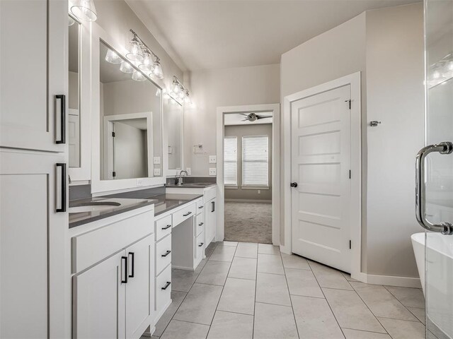 19001 Bobcat Ridge Ct, Cashion, OK 73016 - full bath with tile patterned floors, double vanity, ceiling fan, a soaking tub, and baseboards