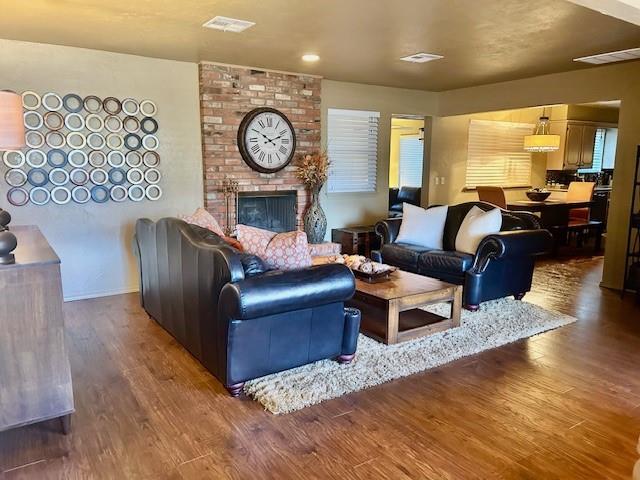 living room featuring dark hardwood / wood-style floors and a brick fireplace