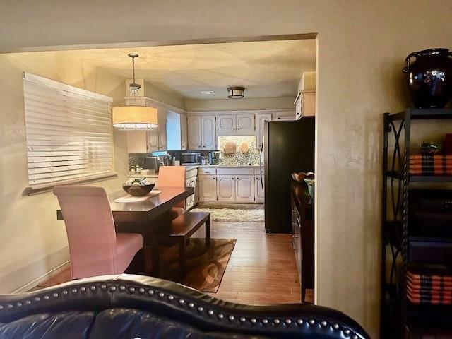 kitchen featuring tasteful backsplash, wood-type flooring, hanging light fixtures, appliances with stainless steel finishes, and white cabinets