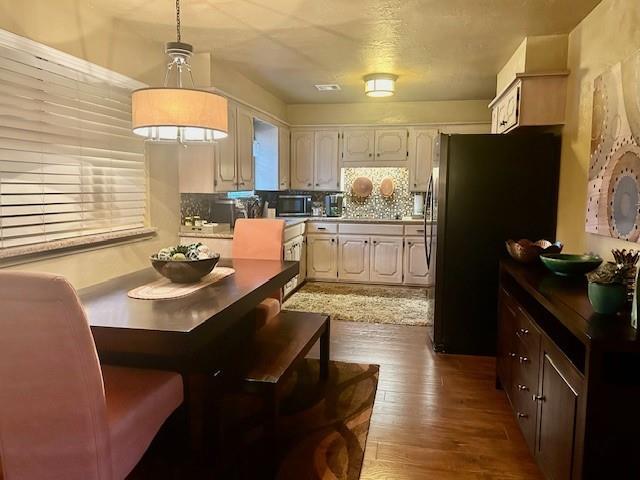 kitchen featuring fridge, decorative light fixtures, hardwood / wood-style floors, and tasteful backsplash