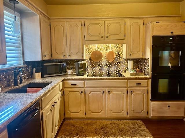 kitchen with sink, backsplash, dark hardwood / wood-style flooring, black appliances, and light stone countertops