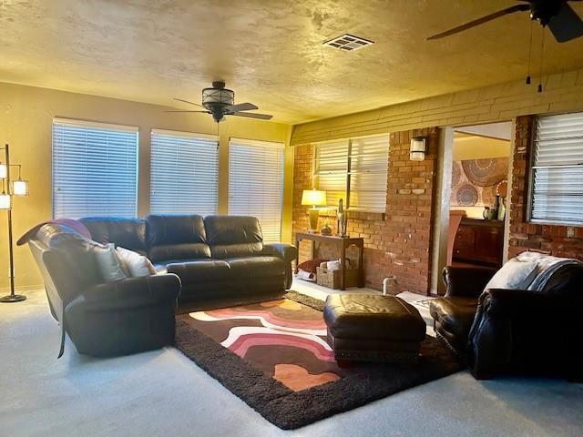 living room with a textured ceiling, ceiling fan, and carpet