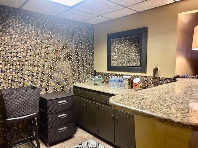 bathroom featuring tile patterned floors, tile walls, and a drop ceiling