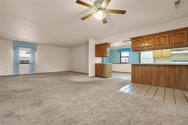 kitchen featuring light carpet, ceiling fan, a healthy amount of sunlight, and white refrigerator