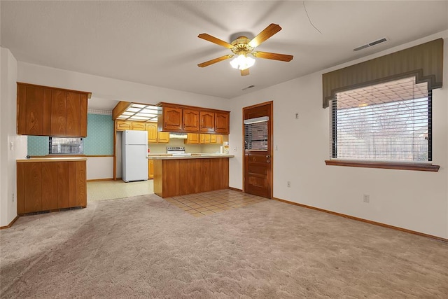 kitchen with ceiling fan, tasteful backsplash, light carpet, kitchen peninsula, and white fridge