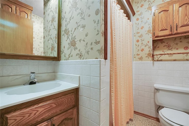 bathroom with vanity, tile walls, and toilet