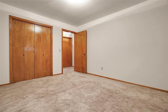 unfurnished bedroom featuring light carpet, a textured ceiling, and a closet