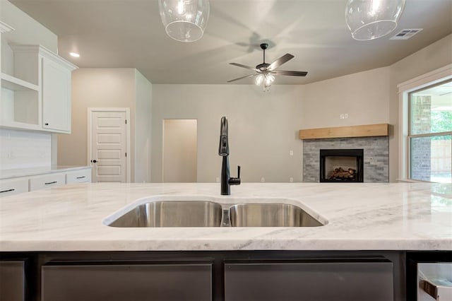 kitchen featuring tasteful backsplash, light stone countertops, sink, and white cabinets