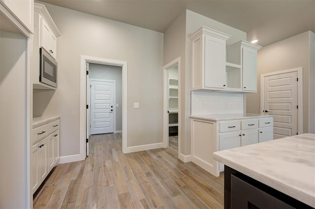 kitchen with white cabinetry, light hardwood / wood-style flooring, and backsplash