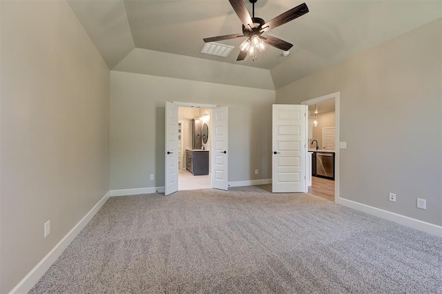 unfurnished bedroom with sink, ceiling fan, ensuite bathroom, light carpet, and vaulted ceiling