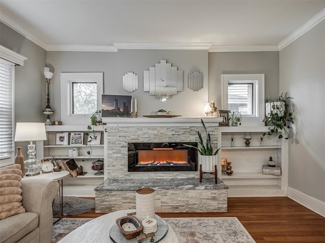 living area featuring a healthy amount of sunlight, crown molding, wood finished floors, and a stone fireplace