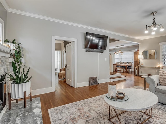 living area featuring a chandelier, a fireplace, crown molding, and wood finished floors