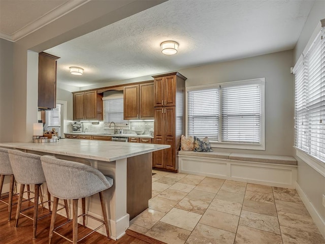 kitchen featuring tasteful backsplash, brown cabinetry, a breakfast bar, a peninsula, and light countertops