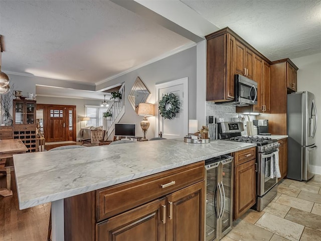 kitchen featuring crown molding, stainless steel appliances, tasteful backsplash, stone tile flooring, and beverage cooler