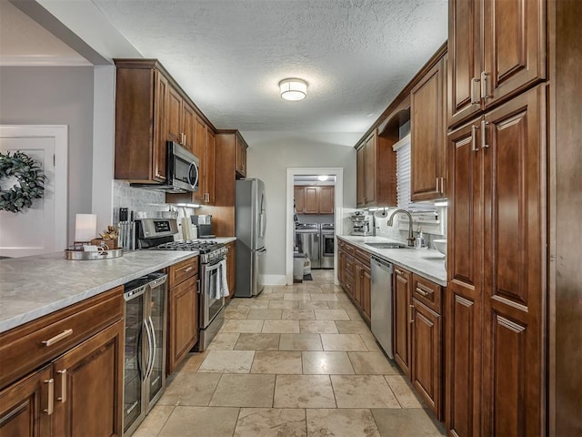 kitchen with wine cooler, stainless steel appliances, decorative backsplash, a sink, and independent washer and dryer