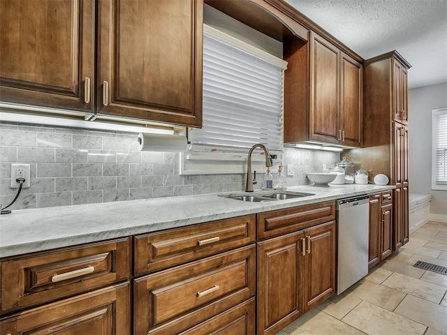 kitchen featuring visible vents, baseboards, decorative backsplash, a sink, and stainless steel dishwasher