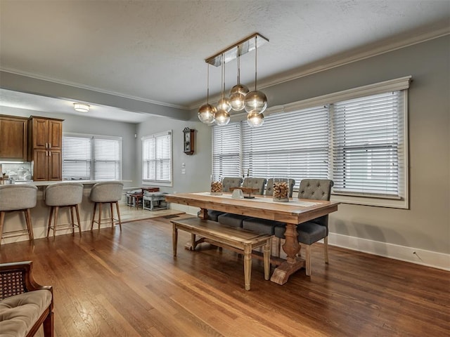 dining area with baseboards, an inviting chandelier, wood finished floors, and crown molding