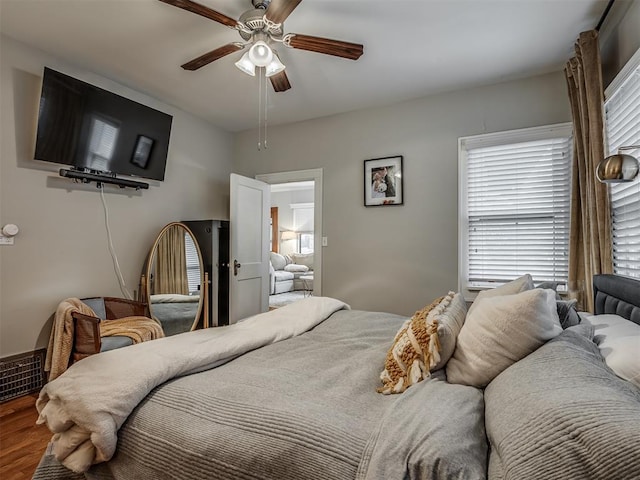 bedroom with ceiling fan, visible vents, and wood finished floors