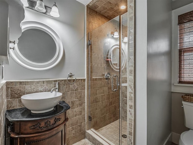 full bathroom featuring toilet, a stall shower, tile walls, and vanity