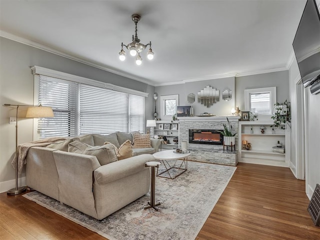 living room featuring crown molding, baseboards, wood finished floors, and a stone fireplace