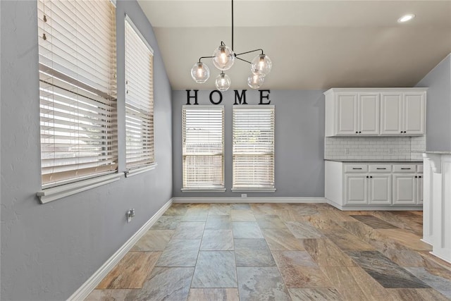 unfurnished dining area featuring a chandelier and vaulted ceiling