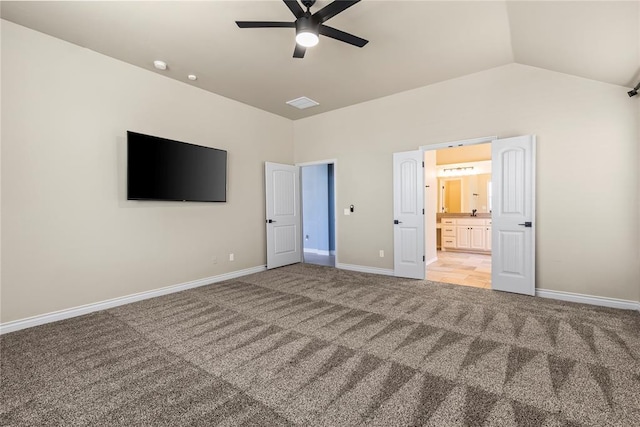 unfurnished bedroom featuring ceiling fan, lofted ceiling, ensuite bathroom, and carpet floors