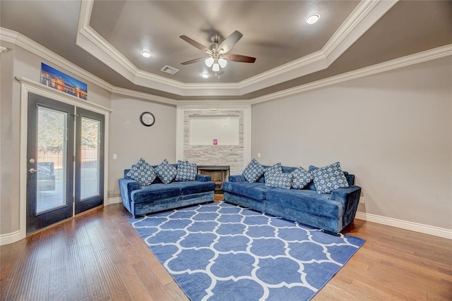 living room with hardwood / wood-style flooring, ornamental molding, and a raised ceiling