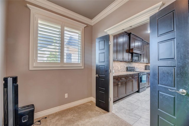 kitchen with stainless steel gas range oven, tasteful backsplash, dark brown cabinets, ornamental molding, and light stone countertops