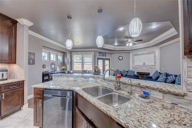 kitchen with decorative light fixtures, sink, stainless steel dishwasher, light stone counters, and a raised ceiling