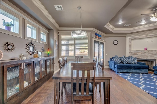 dining space featuring ceiling fan, ornamental molding, a raised ceiling, and wood-type flooring