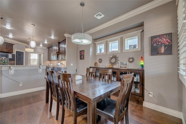 dining room with dark hardwood / wood-style flooring, crown molding, and a healthy amount of sunlight