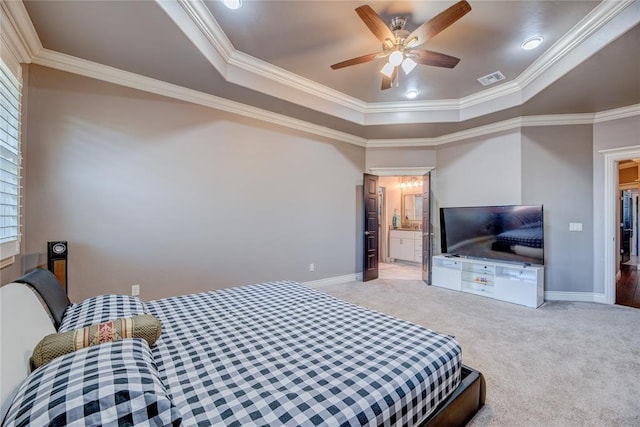 carpeted bedroom with ceiling fan, ornamental molding, a tray ceiling, and ensuite bathroom