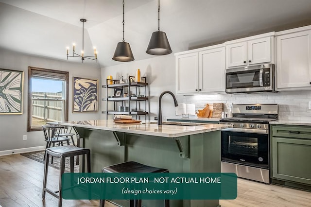 kitchen with pendant lighting, a kitchen island with sink, stainless steel appliances, and white cabinets